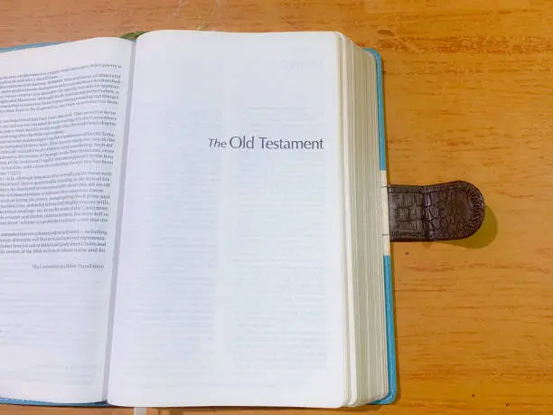 Opened Old Testament Book of the Bible at the top of a wooden table copyspace