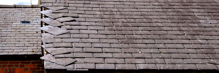 Loose, slates caused by storm damage on a house roof