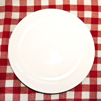 Empty plate on white and red square picnic or trattoria tablecloth