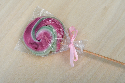 One round, spiral-shaped lollipop packed lies on a light background