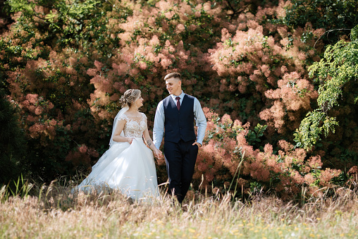 the groom and the bride are walking in the forest on a bright day