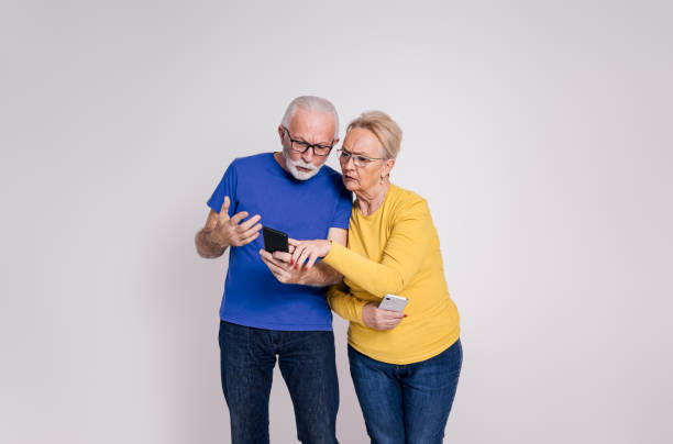 istock Suspicious senior husband checking wife's messages over mobile phone on isolated white background 1894357602