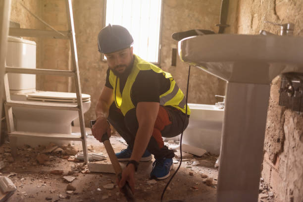 construction worker removes broken tiles with a shovel in a bathroom