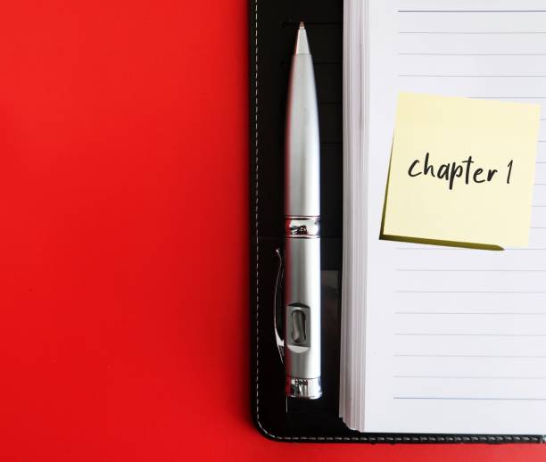 Black notebook, pen on red background with copy space and stick note written CHAPTER 1, concept of start writing book - novel fiction non-fiction, first time writer get start