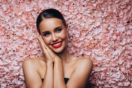 Beautiful emotional woman against the background of a flower wall