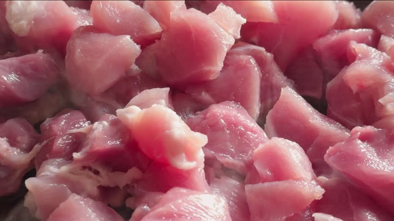 Small pieces of red meat are fried in frying pan, close-up, slow camera movement.