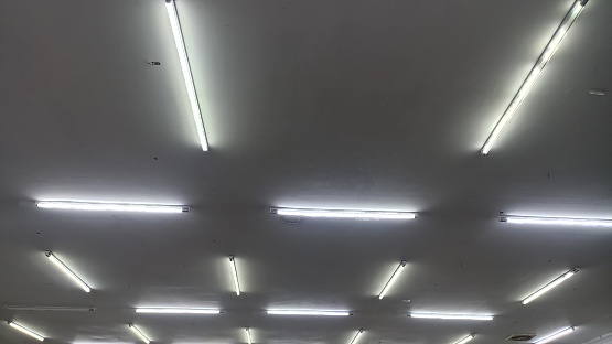 Ceiling with fluorescent lamps. Glowing structure of linear lighting fixtures. Abstract modern architecture background