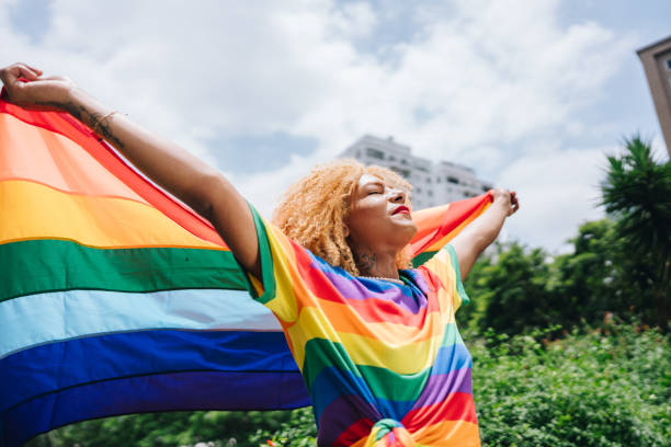Transgender female holding a rainbow flag outdoors