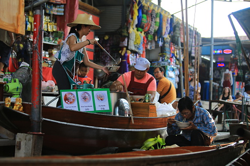 Bangkok Thailand - December 29 2019: a floating noodle restaurant is serving the customer on the river in Damnoen Saduak Floating Market. floating market is one of view point in Bangkok