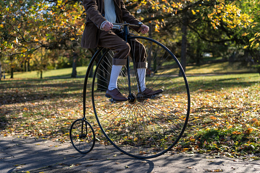 Unidentified man riding a penny farthing bicycle. High wheeler bicycle in park