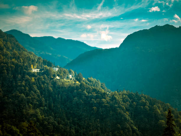 View of Yumthang Valley or Sikkim Valley of Flowers sanctuary, Himalayan mountains, North Sikkim, India. Shingba Rhododendron Sanctuary. Road to valley with foggy Himalayan mounatins and white clouds.