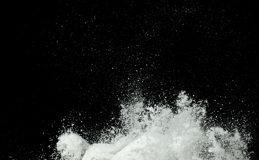 Explosion of snow falling down from sky or roof, heavy big small size snows. Freeze shot on black background isolated. Fluffy White snowflakes splash explode cloud up in mid air storm