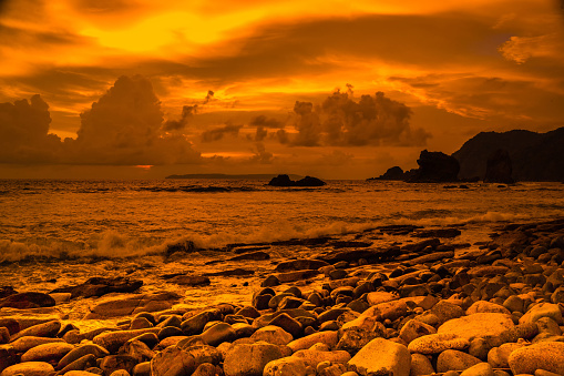 Sunset at the rocky beach in Papuma, Jember, East Java, Indonesia. Cloudy afternoon with ocean waves swipe the sands. Nature and Landscape Photography.