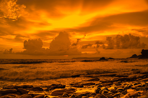 Sunset at the rocky beach in Papuma, Jember, East Java, Indonesia. Cloudy afternoon with ocean waves swipe the sands. Nature and Landscape Photography.