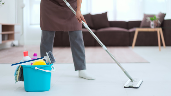 Maid using cleaner equipment in bucket plastic and mop to mopping and cleaning dust on the floor.