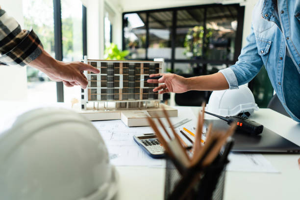 istock Two engineer discussion and brainstorming about condominium model of construction project in office 1894752421