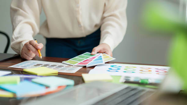 istock Creative graphic designer holding color sample and comparing color swatch on document to designing 1894752424