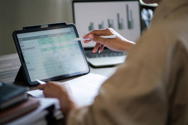 istock Female entrepreneur reading data on tablet and writing notes while working about finance of startup 1894752954