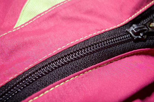 Close-up of the zipper of an old pink and yellow mountain rain jacket