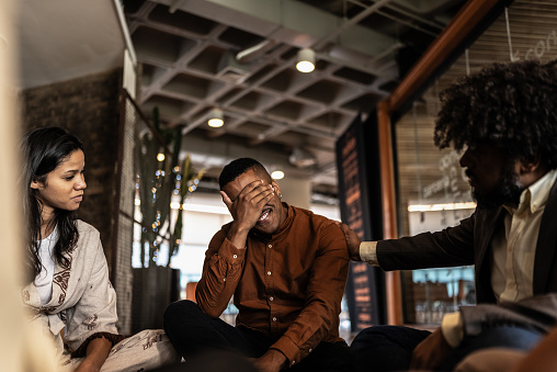 Businessman consoling coworker during group therapy on the office