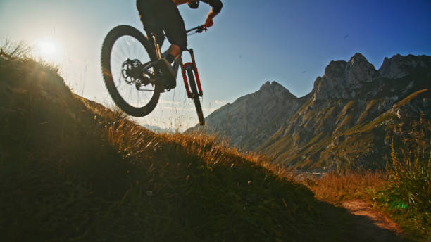 istock Low Angle View of Mountain Biker Performing Stunt on Grassy Hill against Blue Sky during Sunny Day 1894775428