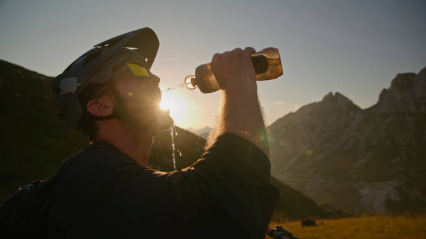 One man, professional male cyclist riding taking a water bottle from bicycle on road.