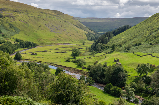 A river runs through the rolling landscape of the southern area of the Yorkshire Dales National Park in England.