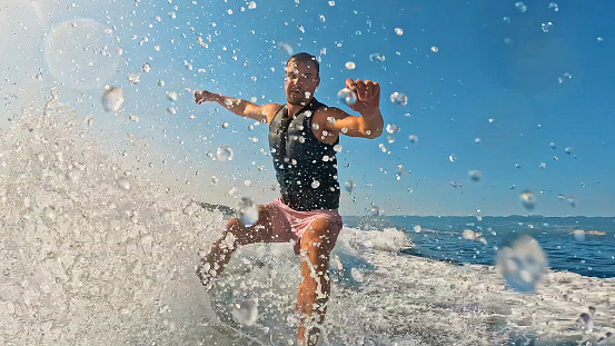 On a Glorious Sunny Day,a Joyful Man Engages in Thrilling Wakeboarding,Creating Mesmerizing Water Splashes in the Beautiful Sea Landscape,Evoking a Sense of Pure Excitement and Freedom.