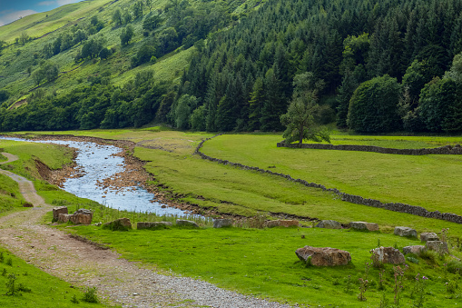 A river runs through the rolling landscape of the southern area of the Yorkshire Dales National Park in England.