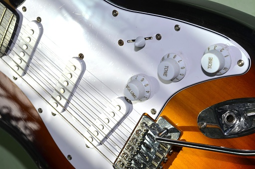 Close-up showing the pickup selector switch and volume control on a vintage style electric guitar, with the guitar's strings, pickguard, bridge and pickups visible in the background.