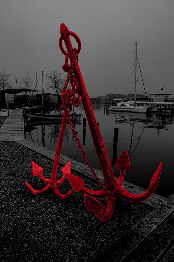 red anchor in front of boats on a lake