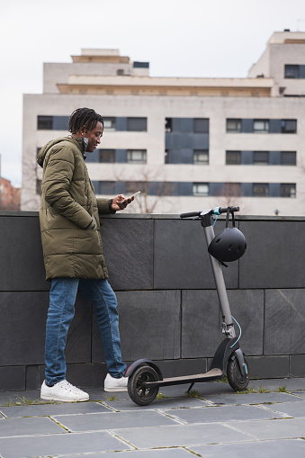 A man is looking his smartphone and enjoys a peaceful ride on their electric scooter. Concept of electrical mobility in the city.