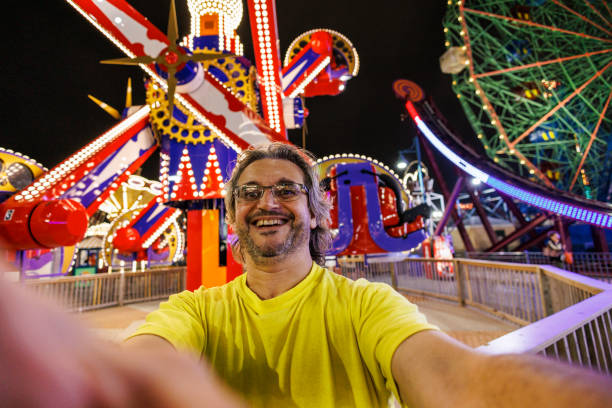 istock Laughing mature bearded man taking selfies in night fairground 1894938840