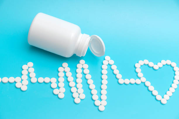 istock An electrocardiogram made of white tablets with a heart symbol. Blue background. A white pill jar. The concept of cardiac medicines. 1894946372
