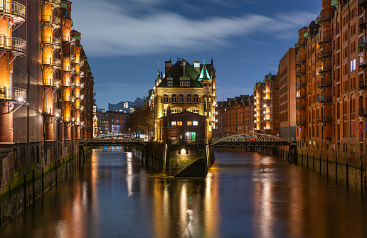 Blick auf das Wasserschloss mit Reflexion im Wasser in der Speicherstadt in Hamburg zur Blauen Stunde am Abend