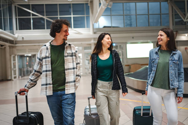 istock Three traveling friends with suitcases on an airport 1894973111