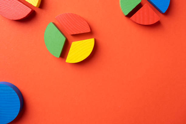 hands working with colorful wooden pie chart pieces on bright red background