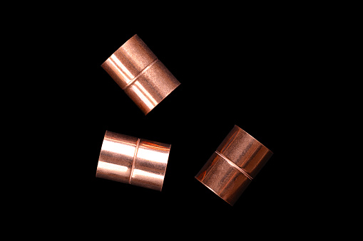Copper sleeves, weld-in sockets, soldering fittings, and connectors for installation on copper pipes, and for use in plumbing or mechanical applications, with 15 mm diameter, on a black background.