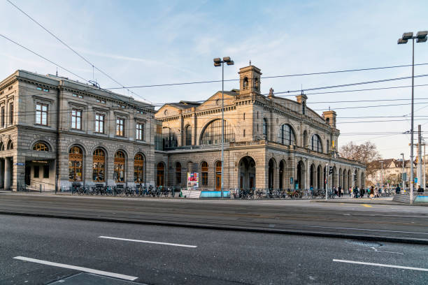Zürich, Switzerland : April 13'2024 -  A building of Zurich Hauptbahnhof or main station with vehicles such cars, motorcycles and bicycles parking in front of the building with sunny day and blue sky.