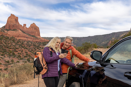 Mature couple explore red rock desert land with vehicle