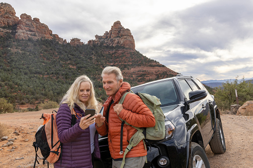 Mature couple explore red rock desert land with vehicle