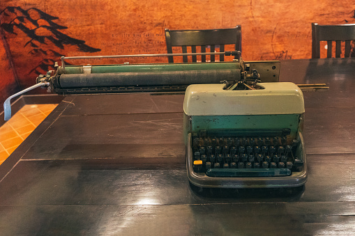 Vintage old aged typewriter on wooden table front concrete wall background. Retro instagram style filtered photo
