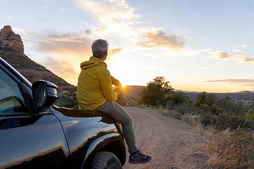Mature man watches sunset over desert from vehicle