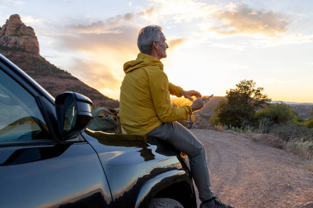 Mature man uses mobile phone from vehicle