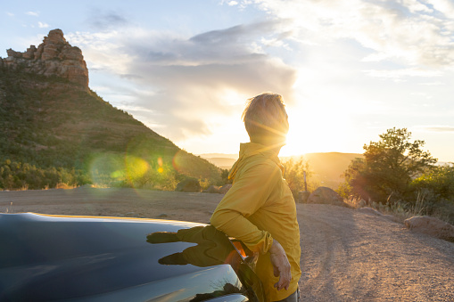 Mature man watches sunset over desert from vehicle