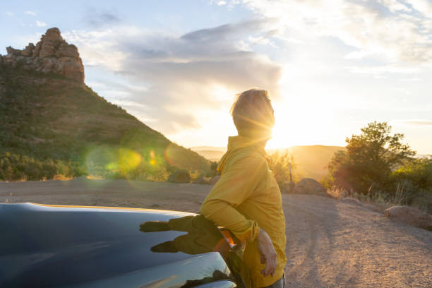 зрелый мужчина наблюдает закат из автомобиля - sun lens flare sedona desert стоковые фото и изображения