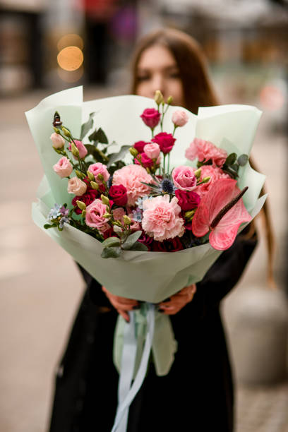 istock Selective focus of delicate flower bouquet of eustoma, carnations, anthurium and eucalyptus in red and pink colors in woman's hands 1895201795