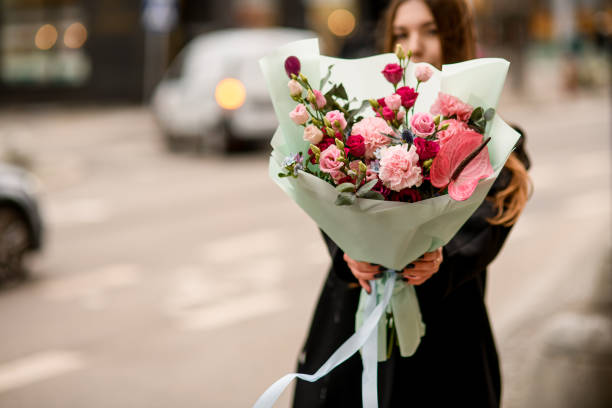 istock Selective focus of beautiful bouquet with eustoma, carnations, anthurium and eucalyptus in red and pink colors in girl's hands 1895202312