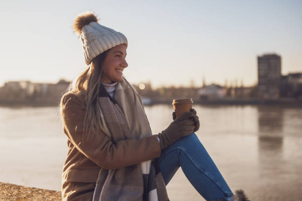 Woman drinking coffee and relaxing outdoor on a sunny winter day - foto de acervo