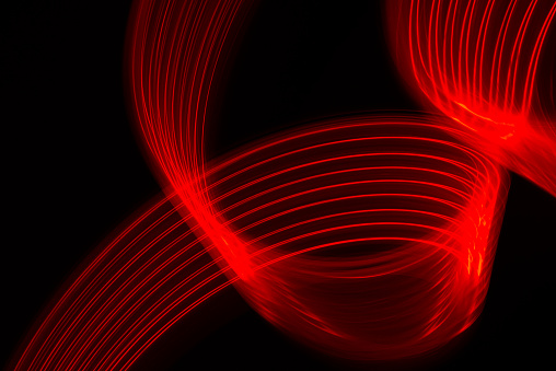 Fiber optic light effect in red color on dark background. Abstract image reflecting futuristic and cutting-edge technology.